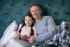 微笑父亲女儿阅读书床上