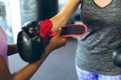 女教练帮助女运动穿拳击手套健身中心