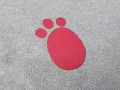 红色的脚打印灰色水泥人行道上