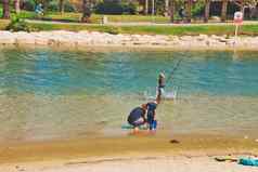 父亲孩子们钓鱼钓鱼杆雅尔璲河电话特拉维夫城市阳光明媚的夏天一天