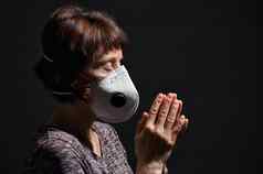 女人穿医疗保护病毒面具祈祷