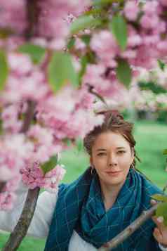 肖像年轻的快乐微笑红发女人白色毛衣蓝色的围巾开花粉红色的樱花树花城市公园基辅乌克兰