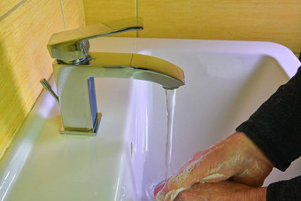 洗手男人。冲洗肥皂运行水水槽冠状病毒流感大流行预防洗手肥皂温暖的水摩擦指甲手指洗经常手洗手液过来这里