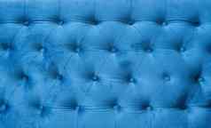 丝绒表面沙发特写镜头coach-type丝绒冗长的收紧按钮蓝色的切斯特菲尔德风格绗缝室内装潢背景关闭