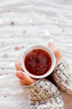 女人持有杯热茶茴香明星冬天织物背景闪闪发光的银雪花