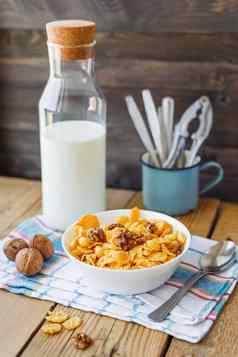 美味的玉米片核桃碗瓶牛奶乡村木背景格子餐巾健康的脆皮早餐零食