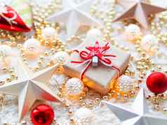 圣诞节一年明星装饰白色针织背景现在盒子包装工艺纸明星象征金属光灯泡精致的模式金珠子红色的球