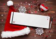 圣诞节一年背景感觉心红色的圣诞老人的他记事本笔圣诞节装饰星星银闪闪发光的雪花五彩纸屑木表格的地方文本