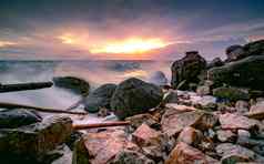 海洋水飞溅岩石海滩美丽的日落天空
