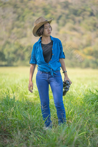 女人穿他持有双筒望远镜草场