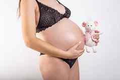 特写镜头怀孕了女人的肚子鼠标玩具美丽的怀孕了女人怀孕为人父母准备期望概念