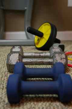 行哑铃坐着地毯的地板上首页健身房锻炼首页锻炼设备住活跃的健身房关闭