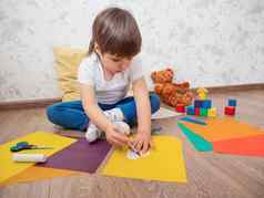 蹒跚学步的男孩学习减少彩色的纸剪刀孩子坐在