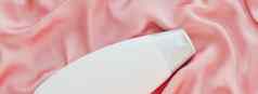 空白标签化妆品容器瓶产品模型粉红色的丝绸背景