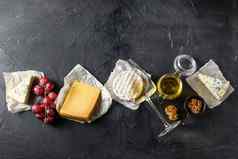 奶酪开胃菜选择抱怨零食集各种模具法国奶酪葡萄山核桃坚果白色长相思酒蜂蜜黑色的背景前视图复制空间