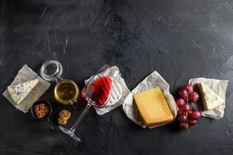 分类奶酪质antipasto玻璃红色的酒蜂蜜坚果香料黑色的背景石头板岩前视图免费的空间文本前视图