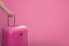 手持有旅行者粉红色的手提箱小屋大小行李销