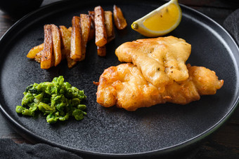 鱼芯片传统的英国热菜组成炸鱼土豆芯片糊状的豌豆鞑靼酱汁服务黑色的板黑暗木表格酒吧一边视图
