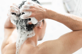 特写镜头年轻的男人。洗头发洗发水浴室