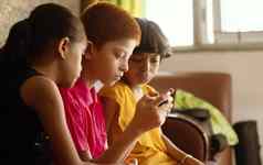多少数民族孩子们兄弟姐妹忙玩游戏移动首页概念儿童移动视频游戏上瘾技术互联网智能手机