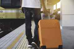 男人。拖橙色手提箱行李袋走火车国家