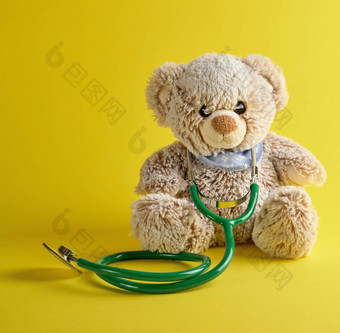 灰色的泰迪熊绿色医疗听诊器黄色的后台