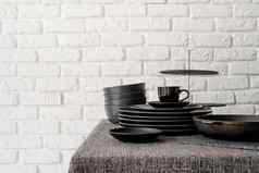 堆栈黑色的陶瓷菜餐具表格白色砖墙背景