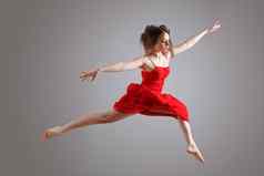 优雅的女舞者红色的衣服跳灰色的背景