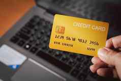 购物在线正常的概念手持有黄色的信贷卡模糊的移动PC背景支付买在线首页