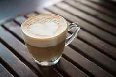关闭卡布奇诺咖啡杯心形状的牛奶模式咖啡馆