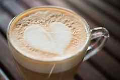 关闭卡布奇诺咖啡杯心形状的牛奶模式咖啡馆