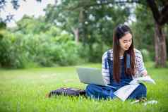 美丽的亚洲女孩学生持有书微笑相机学习教育概念公园夏天放松时间