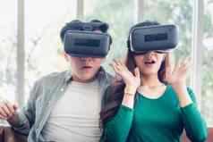 年轻的夫妇有趣的看视频虚拟现实夫妇爱享受电子护目镜游戏沙发上娱乐创新生活方式概念