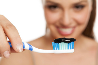 年轻的女人持有牙刷黑色的<strong>牙膏</strong>