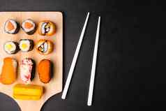 前视图寿司集木托盘筷子黑色的背景日本食物免费的空间文本