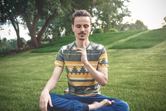 年轻的男人。冥想在户外公园坐着眼睛关闭手享受自然瑜伽冥想概念精神上的实践Zen