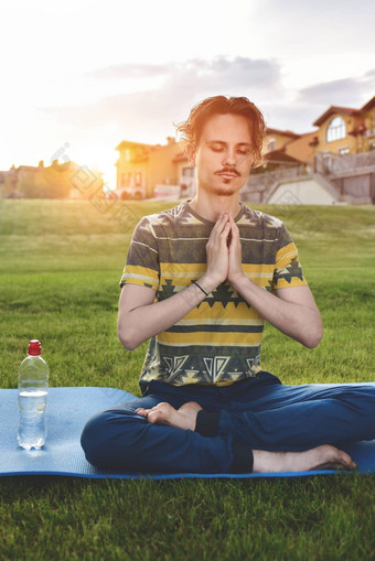 年轻的男人。冥想在户外公园坐着眼睛关闭手享受自然瑜伽冥想概念精神上的实践Zen