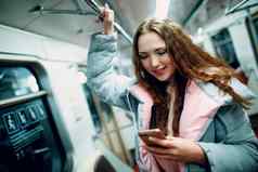年轻的女人微笑移动电话地铁地铁概念