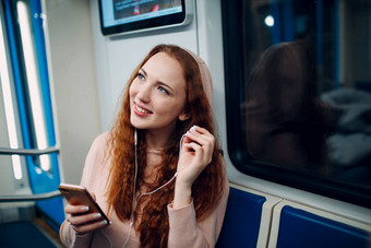 年轻的女人听音乐移动电话地铁地铁概念