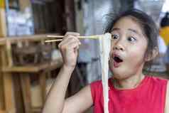 亚洲孩子女孩红色的衣服吃小面条汤