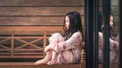 孤独的亚洲孩子坐着窗口