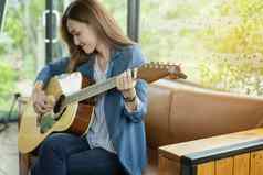 美丽的女孩玩吉他窗口教育Lifest