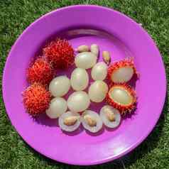 关闭红毛丹去皮水果前视图健康的水果紫色的背景准备好了吃甜蜜的巴厘岛水果水果圆形的椭圆形single-seeded浆果覆盖肉质柔软刺