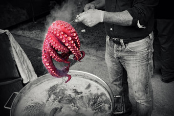 男人。手套持有红色的章鱼准备好了煮
