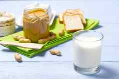 美国早餐牛奶花生黄油花生黄油白色面包玻璃牛奶蓝色的木背景