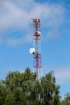 红白电信塔前绿色树蓝色的天空云背景