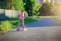 女孩游乐设施粉红色的辊溜冰鞋沥青夏天孩子学习骑辊溜冰鞋滑冰