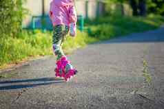 女孩游乐设施粉红色的辊溜冰鞋沥青夏天照片脸回来