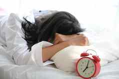 亚洲女人懒惰的睡眠醒着的床上时钟白色贝德