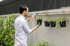 年轻的但浇水植物盆栽植物可回收的塑料瓶浇水植物扭曲的塑料瓶回收年轻的男人。工作花园